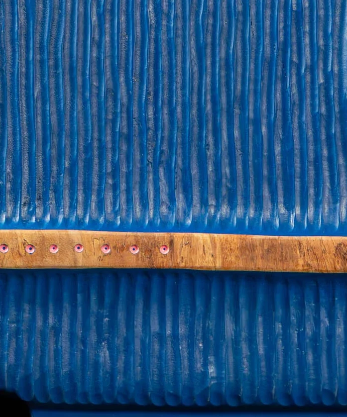 Movimento Azul — faixa de madeira nua atravessando a face azul, com pinos rosa em fila